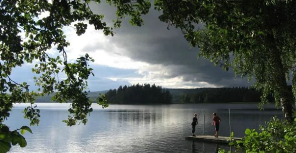 En fridfull sjö omgiven av skog och öppen natur, med moln på himlen ovanför, vid Sölje Camping.