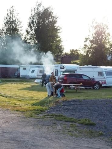 Alt-text: "Flera husvagnar och campingfordon parkerade på Lofsdalen camping, omgivna av natursköna landskap."