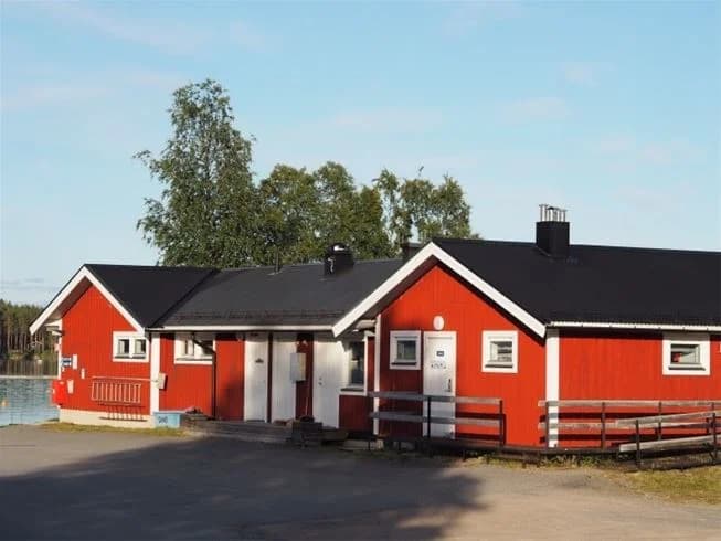 En mysig stuga med ett sluttande tak och träpaneler vid Lofsdalen camping, omgiven av naturlig skogsmiljö.