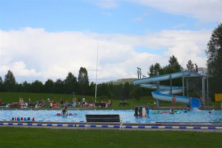 En grönskande park med områden för rekreation och fritid på Vännäs bad & camping, omgiven av träd och öppna ytor.