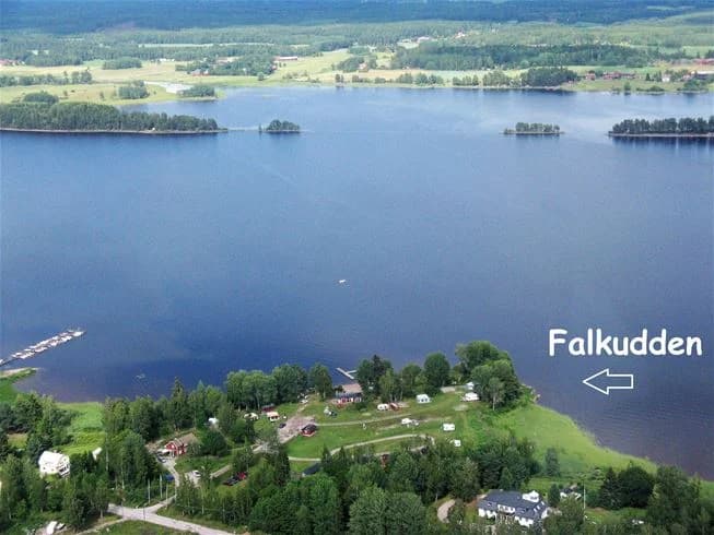 Flygfoto över Falkuddens camping, café och stugby, med sjö och kustlinje i bakgrunden.