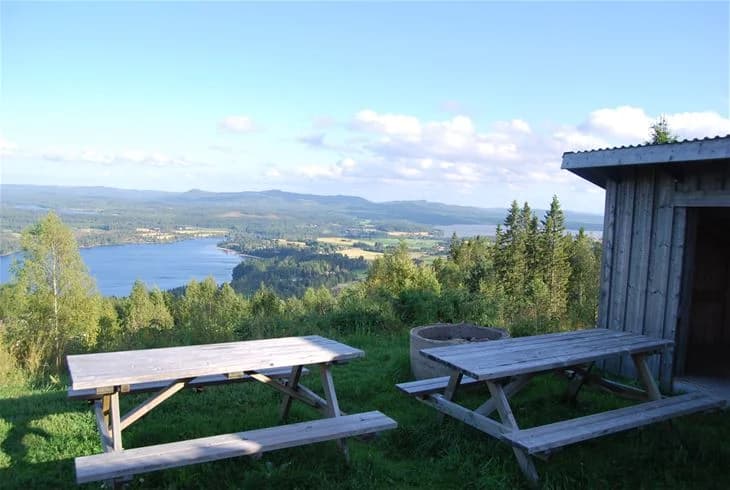 En vacker landskapsvy över Orbadens camping med en picknickbordsmöbel i förgrunden, omgiven av höga kullar och naturskön omgivning.