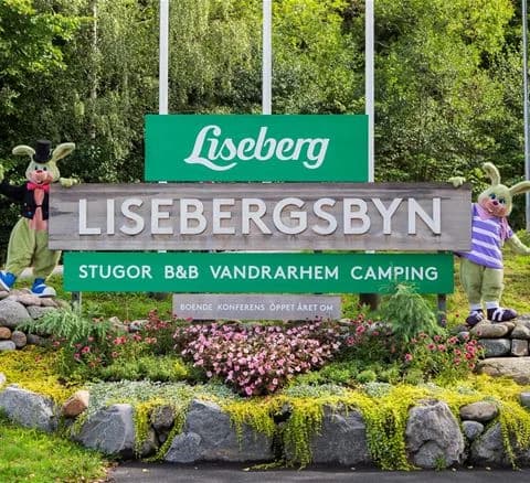 En grönskande park vid Lisebergsbyn med frodig växtlighet och välklippta gräsmattor, inbjudande för rekreation och avkoppling.