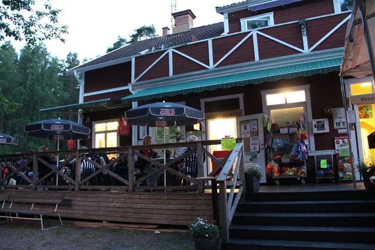 En cykel står parkerad utanför en campingstuga på Malmköpings bad & camping, omgiven av en lugn och naturnära miljö.