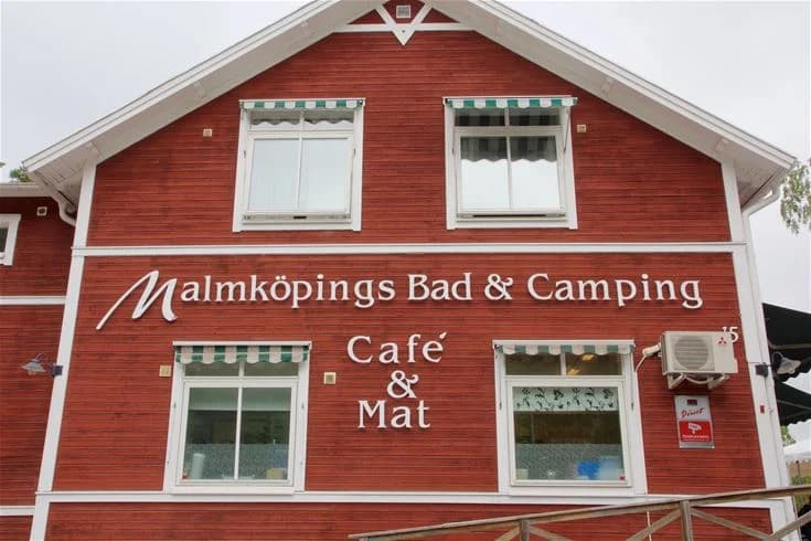 En cykel parkerad vid sidan av en byggnad på Malmköpings bad & camping, med utemöbler i bakgrunden.