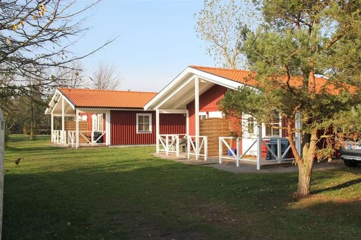 En mysig stuga omgiven av grönska med en välskött gräsmatta och uteplats, belägen vid Stenåsa Stugor & Camping.
