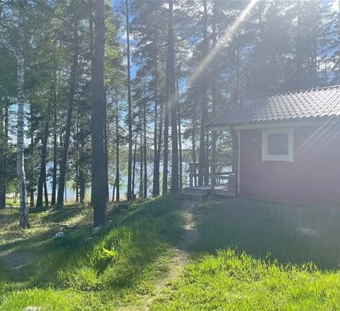 En mysig campingplats omgiven av grönskande träd och gräs, med en trästuga i mitten.