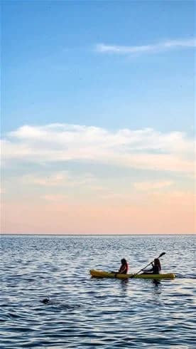 En kajak paddlar på det lugna vattnet nära horisonten vid Kalmar Camping - Rafshagsudden.