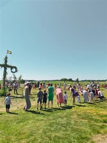 En solig dag på Kalmar Camping - Rafshagsudden med grönskande gräs, en molnig blå himmel och många besökare som njuter av friluftsliv och rekreation.