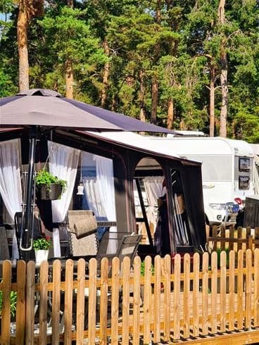 En skuggig trädgård med tält och utomhusmöbler på Kalmar Camping - Rafshagsudden.