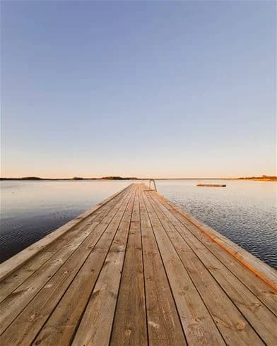 En träbrygga sträcker sig ut över vattnet med horisonten i bakgrunden på Kalmar Camping - Rafshagsudden.