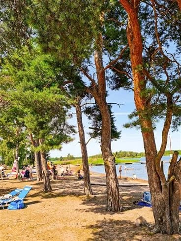 En solig sommardag på Kalmar Camping - Rafshagsudden, där människor njuter av avkoppling vid stranden med utsikt över kusten.