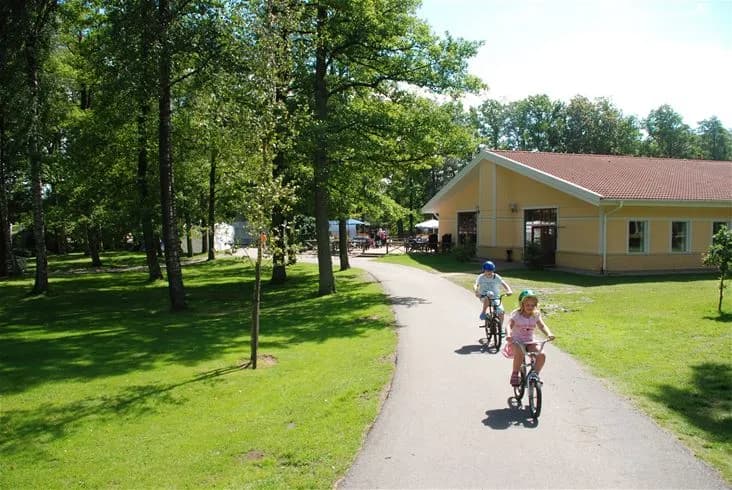 En cykel står parkerad på en grönskande plats med träd i bakgrunden, vilket antyder en avkopplande rekreationsmiljö vid Gullbrannagården.