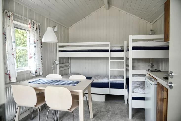 Ett mysigt sovrum med våningssängar i en trästuga på Gullbrannagården. Rummet har trägolv och träpaneler på väggarna, vilket skapar en varm och ombonad känsla.