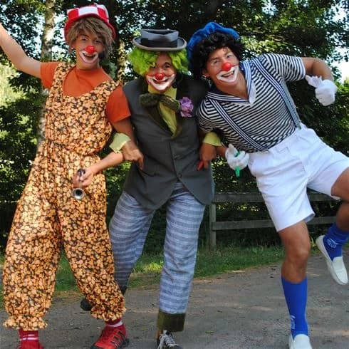 En clown med hatt och kostym ler glatt under ett evenemang på Gullbrannagården, vilket skapar en festlig och underhållande atmosfär.