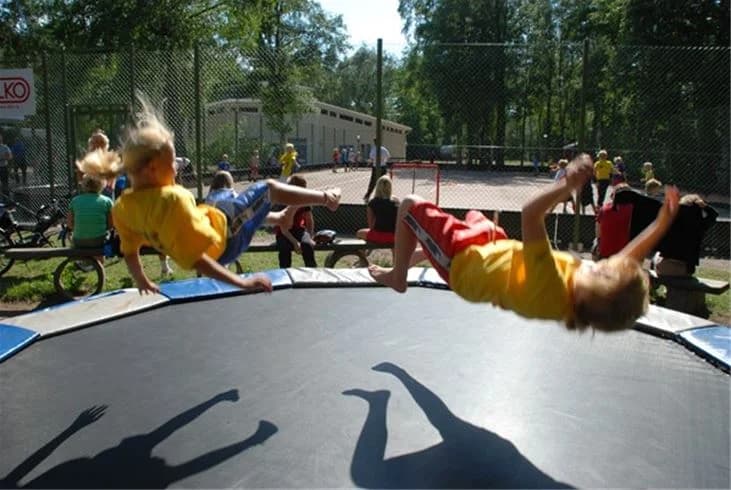 En glad barn hoppar på en trampolin och omsluts av ett skyddsnät, vilket signalerar en dag fylld av lek och nöje på Gullbrannagården.