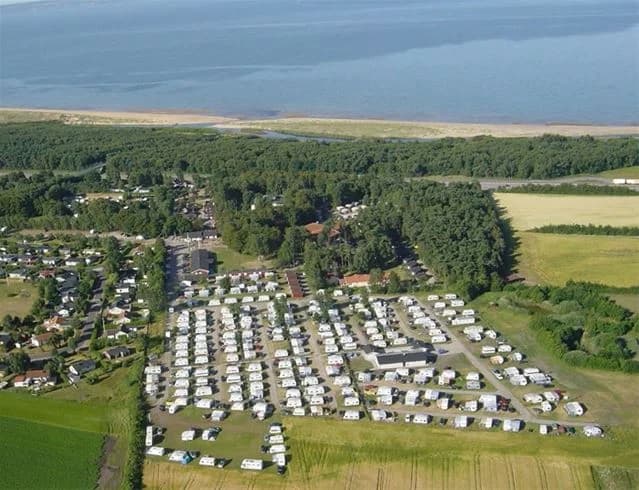 Flygbild över Gullbrannagården med utsikt över kusten, där stranden möter det blåa havet. Området präglas av en tropisk känsla med rekreationsmöjligheter och en semesterort.