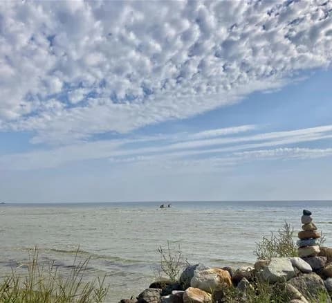 En vy över Wikegårds semesterby & ställplatscamping med en klar blå himmel och vita moln över ett stilla hav.