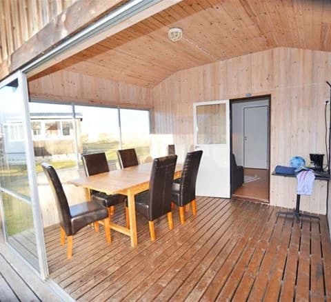 Ett interiörfoto från Wikegårds Semesterby & Ställplatscamping som visar ett rum med träinredning. Golvet är av trä, och taket har träpaneler. Det finns en dörr och rummet präglas av en varm och naturlig atmosfär tack vare träets färger och strukturer.