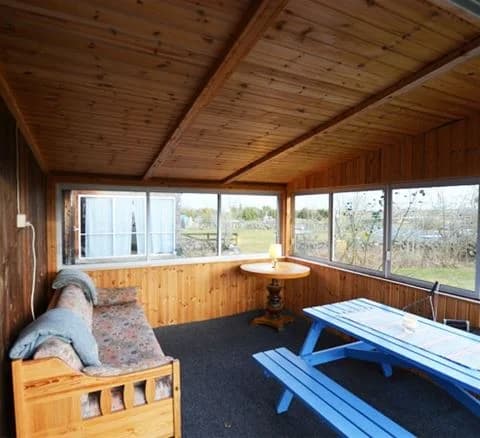Interiör av en semesterstuga på Wikegårds Semesterby & Ställplatscamping. Rummet har träväggar och tak, samt golv av trä. Möbelarrangemanget är enkelt och funktionellt, vilket skapar en mysig och naturlig atmosfär.