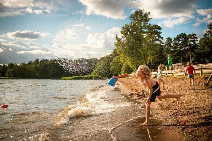En solig dag vid Bredsands bad & camping med människor som njuter av sommarens lediga stunder vid sjön.