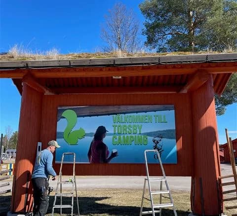 En mysig campingplats med en rustik timmerstuga omgiven av gröna träd och skugga. Perfekt för avkoppling och friluftsliv.