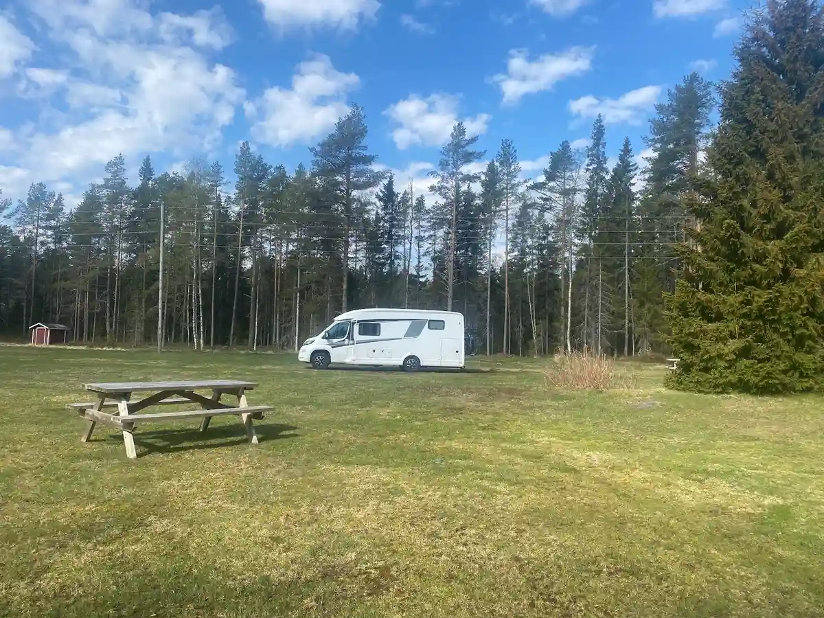 En campingplats med gröna gräsmattor, träd och husvagnar.