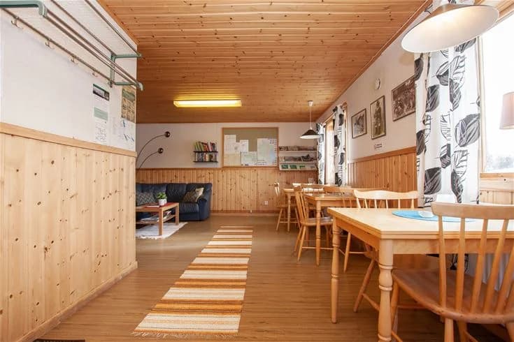 En mysig, träinredd stuga med trägolv och tak, belägen på Rätans camping. Stugan har enkla möbler och skapar en rustik och hemtrevlig atmosfär.