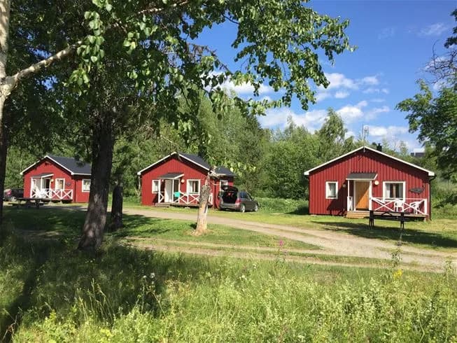 En lantlig campingplats vid Norråkers Camping med stugor omgivna av gräsmarker och ängar.