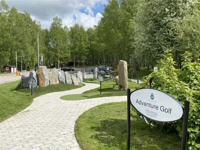 En grön och välskött campingplats vid Skokloster med prunkande trädgårdar och öppna gräsytor, omgivna av noggrant anlagd landskapsdesign och ständigt gröna växter.