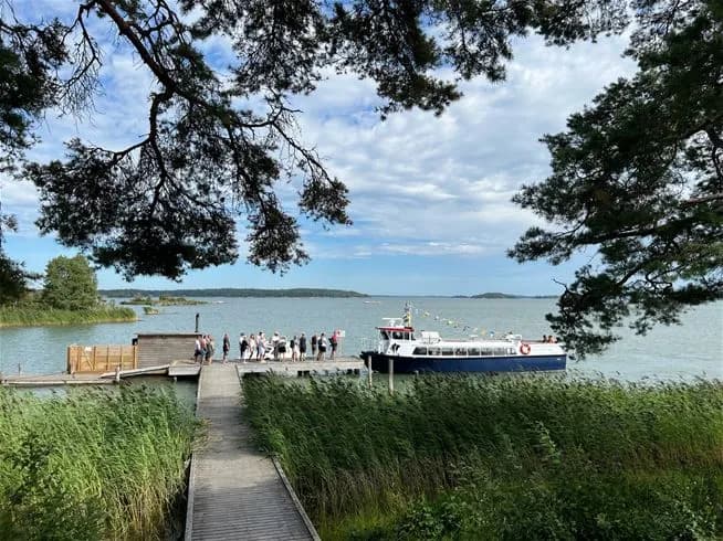 Utsikt över Trosa havsbad & camping med kustlinje, sandstrand och klart vatten under en solig dag.