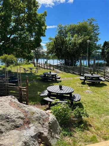 En picknickplats med bord och bänkar i ett naturskönt område vid Trosa Havsbad & Camping.