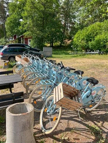 En cykel parkerad vid en campingplats nära havet, med fokus på cykelns hjul, ram och styre.