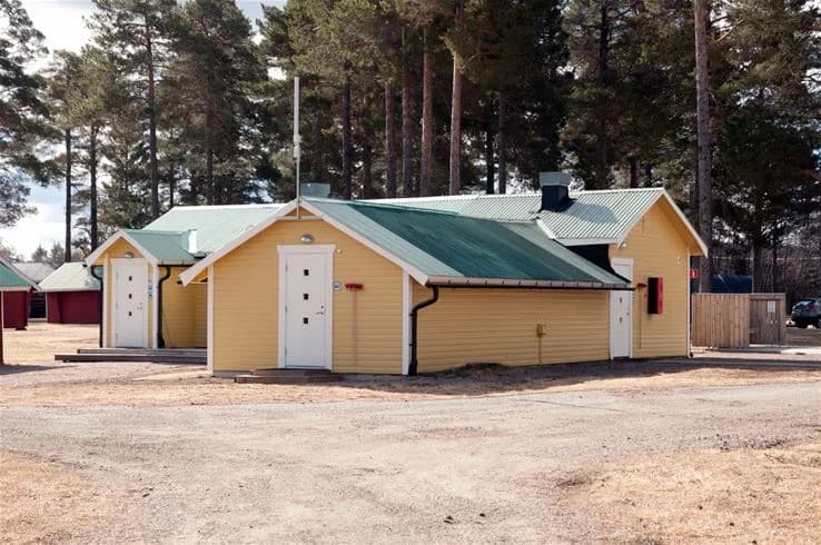 En trästuga med snedtak och enkla fasader, omgiven av natur, tillhör camp viking.