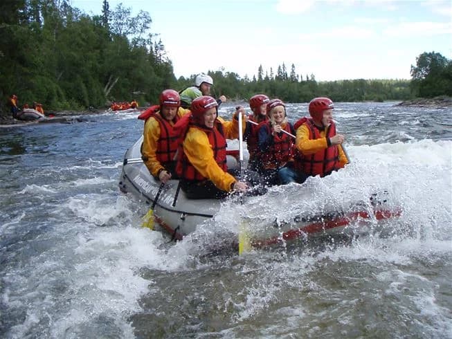 En uppblåsbar båt på en bred flod vid Åre Camping, omgiven av frodig grönska och vacker natur. Perfekt för äventyrslystna besökare som vill utforska området via vatten.