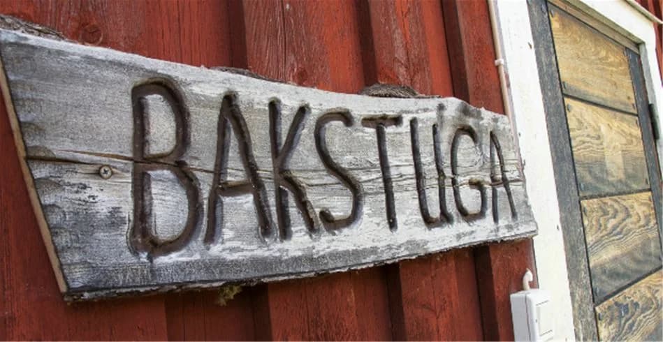 En träskylt med bruna plankor och färgad text, uppställd vid Åre Camping. Skylten omges av träpaneler och målat trä, vilket ger en rustik känsla.