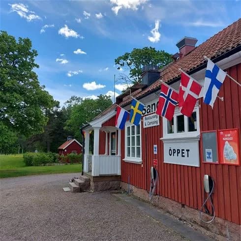 En campingplats med en flaggstång i förgrunden på Sandaholm Restaurang & Camping.