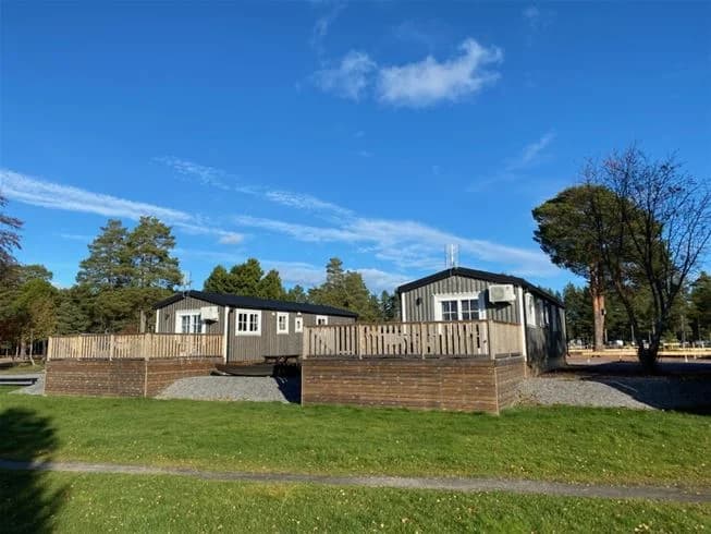 En campingplats vid Stenö havsbad med flera stugor och mobila hem utspridda på ett stort grönområde. Stugorna är omgivna av välskötta gräsmattor och träd som ger skugga.