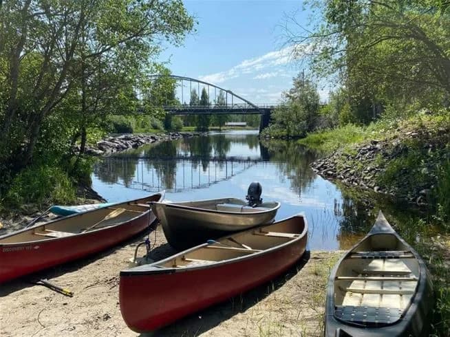 En kanot flyter på en lugn flod vid Ammeråns fiskecamp, omgiven av frodig grönska och en stillsam atmosfär.