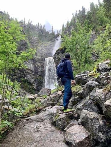Ett naturskönt vattenfall forsar ner över klippformationer i vildmarken nära Åsarna Skicenter, omgiven av frodig grönska och skapar en inbjudande plats för utomhusäventyr och rekreation.