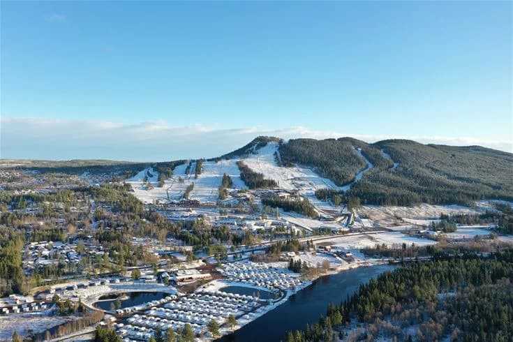 Luftfoto över Kläppens camping under vintern, med snötäckta landskap och småbåtshamn i fjärran.
