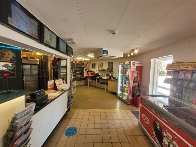 En restaurang med snabbmatsalternativ vid Älvkarleby fiskecamping, med en disk för beställning och meny i bakgrunden.