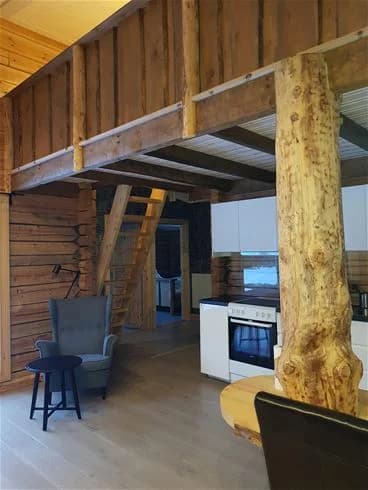 Bild av ett rum på Ammeråns fiskecamp. Rummet har träinredning med ett trägolv och ett tak i träpanel. Det finns också träfärgade möbler som förstärker den rustika och naturliga atmosfären.