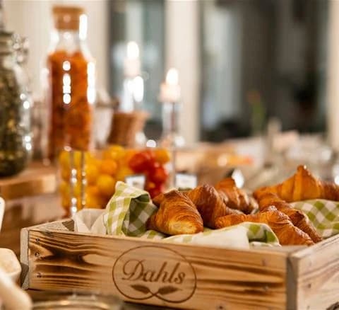 Ett dukat frukostbord med croissanter, frukt och annan plockmat på Lisebergsbyns besöksmål.