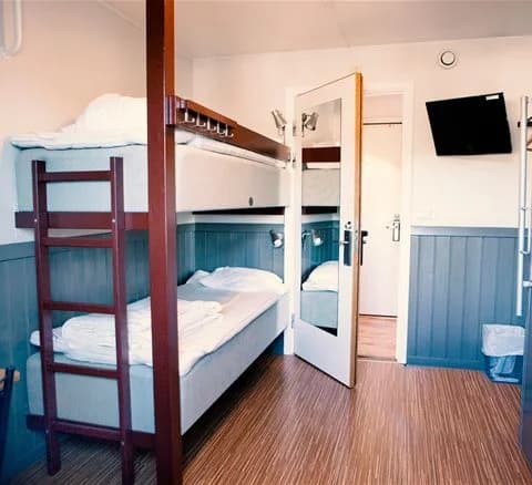 Alt-text: En enkel och inbjudande sovsal på Lisebergsbyn med träinredning, två våningssängar och trägolv.