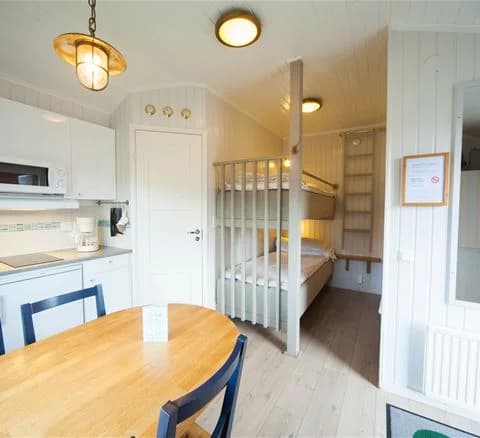 En bild av ett interiört utrymme i Lisebergsbyn visar ett välkomnande och stilrent rum med träelement, inklusive träväggar, trägolv och trädetaljer i inredningen. Möbelarrangemanget ger en inbjudande känsla med fokus på enkelhet och funktion.