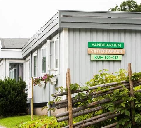 En mysig stuga omgiven av en välskött trädgård med buskar och markbeklädnad, belägen i Lisebergsbyn.