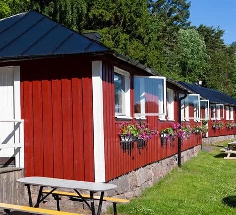 En mysig stuga i skuggad trädgårdsmiljö vid Lisebergsbyn, omgiven av grönska och en välskött bakgård.