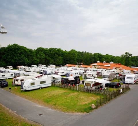 Flygbild över Lisebergsbyn som visar en parkeringsplats med flera husbilar och omgivande grönområden.