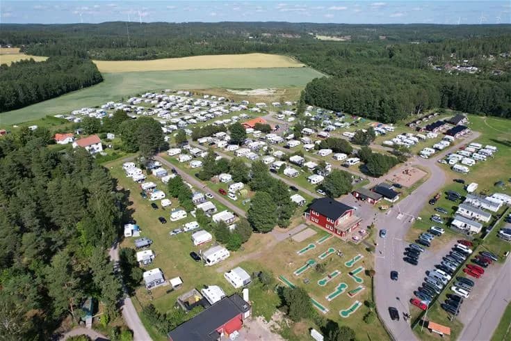 Fågelperspektiv av Harge Bad & Camping med vidsträckt grönområde och campingplatser, inramat av omgivande natur.